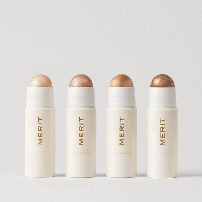 Master ||  Four stick highlighters with the brand name MERIT written on it, with the product cap removed, revealing the highlighter balm