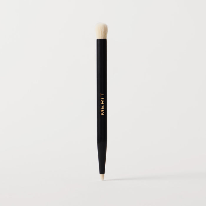 ** | listing A black cosmetic brush with a flat, dual-ended design, featuring the brand name 'MERIT' in gold lettering on the side.