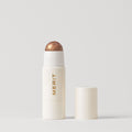 Master || A stick highlighter with the brand name MERIT written on it, with the product cap removed, revealing the highlighter balm