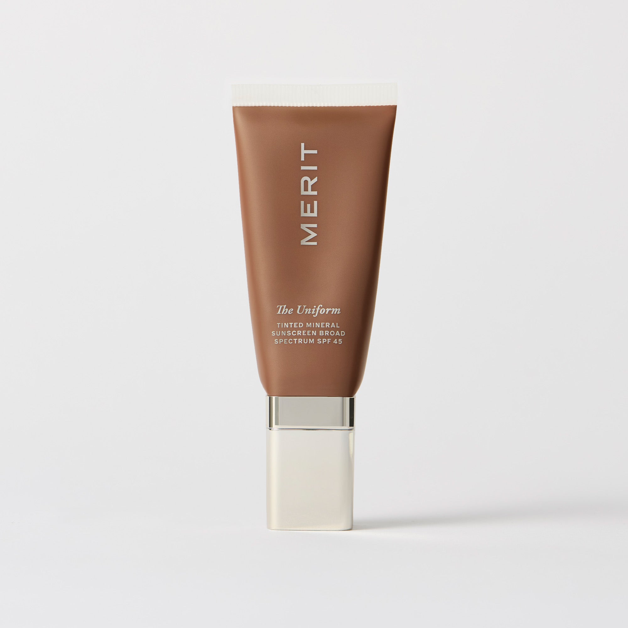 Master || A tube of MERIT brand mineral sunscreen with a sheer tint finish, providing broad spectrum 45 UVA/UVB protection, displayed against a white background. Shade 06