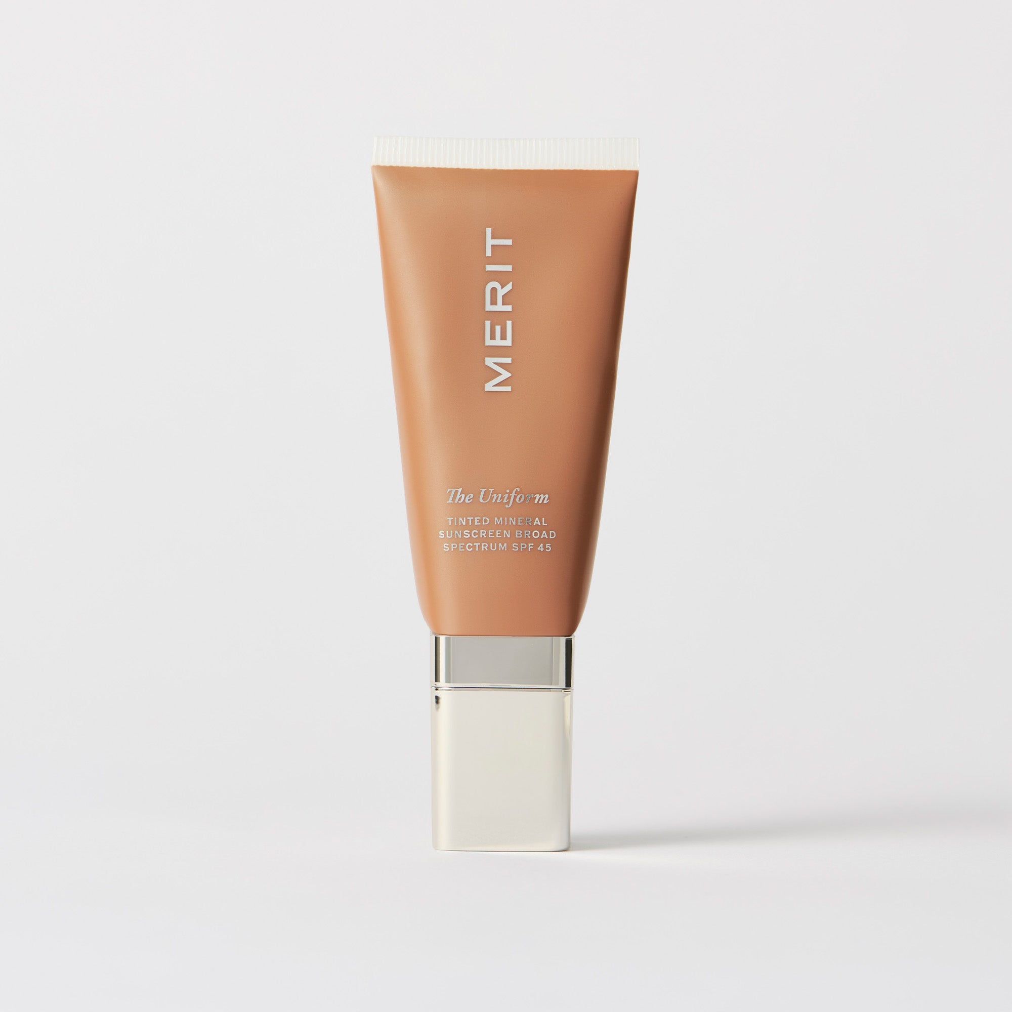 Master || A tube of MERIT brand mineral sunscreen with a sheer tint finish, providing broad spectrum 45 UVA/UVB protection, displayed against a white background. Shade 12