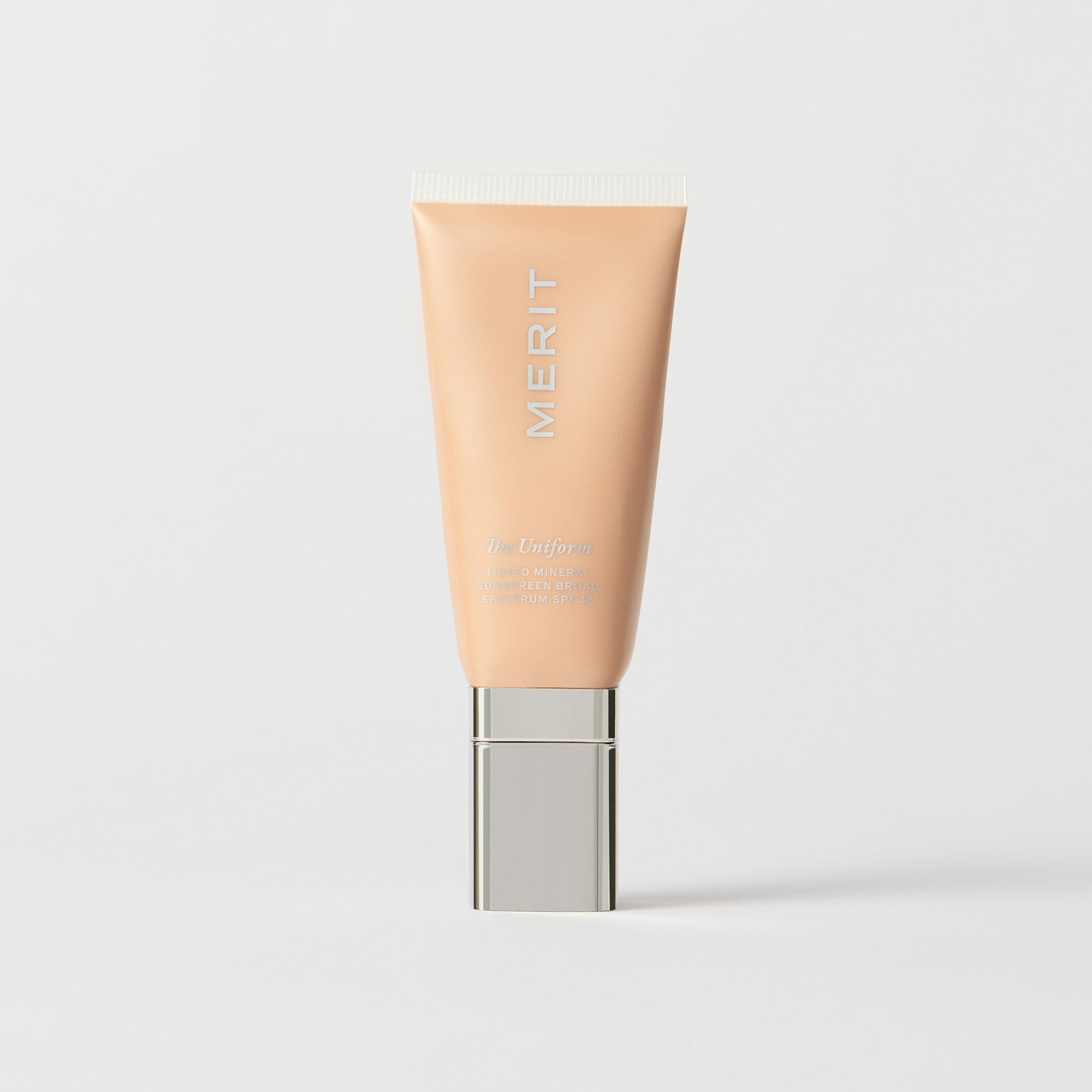 Master || A tube of MERIT brand mineral sunscreen with a sheer tint finish, providing broad spectrum 45 UVA/UVB protection, displayed against a white background. Shade 28