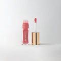 Master ||  A bottle of Merit lip oil with a pearlescent pink shade displayed next to its applicator.