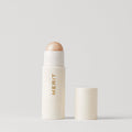 Master ||  A stick highlighter with the brand name MERIT written on it, with the product cap removed, revealing the highlighter balm.